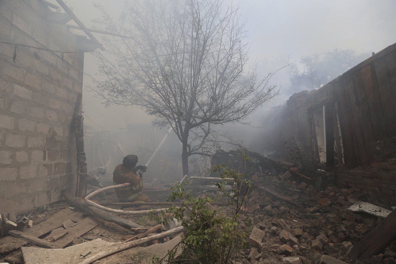 Räddningsarbetare försöker släcka en brand i en byggnad som förstörts av en rysk drönare i Zaporizjzja i Ukraina på måndagen. Foto: Kateryna Klochko/AP/TT