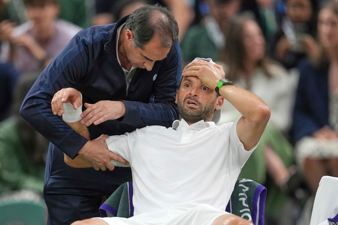 En bedrövad Grigor Dimitrov får behandling under matchen mot Jannik Sinner. Foto: Kin Cheung/AP/TT