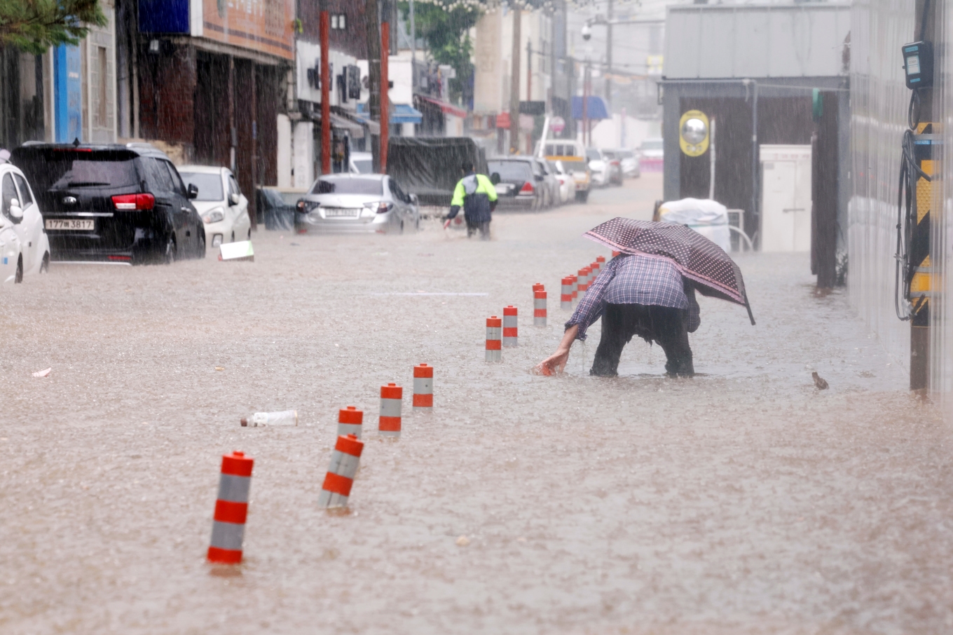 Människor vadar genom skyfallen i staden Gwangju i Sydkorea. Foto: Jeong Dae-eum/AP/TT