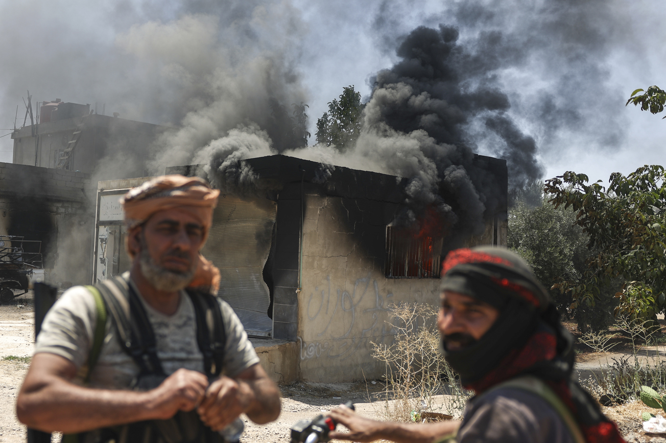 Beduinkrigare framför en nedbränd affär i byn Mazraa i utkanterna av staden Sweida i södra Syrien. Foto: Ghaith Alsayed/AP/TT