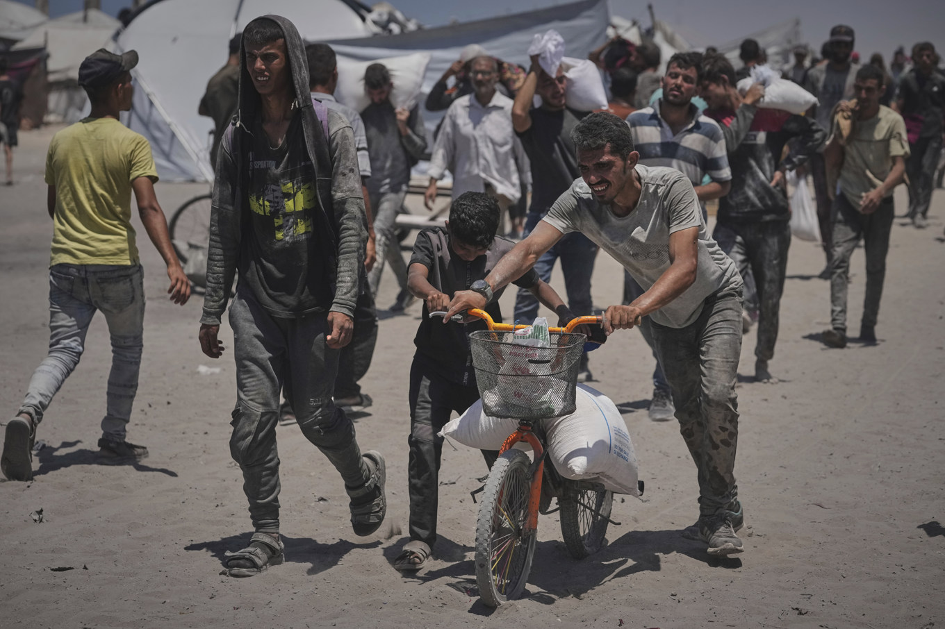 Palestinier bär säckar av förnödenheter som delats ut i Gaza stad. Foto: Jehad Alshrafi