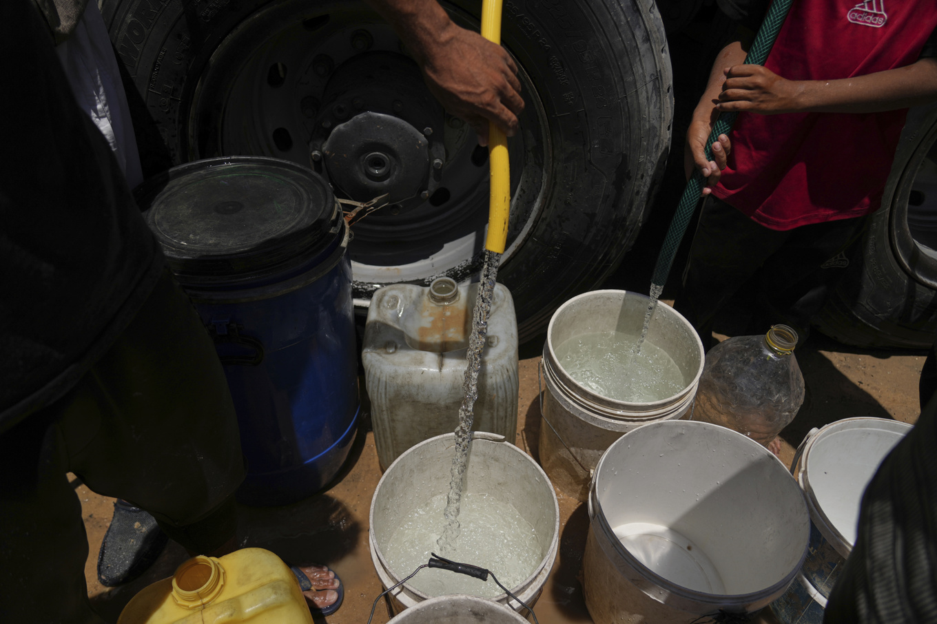 Palestinska flyktingar hämtar vatten från en lastbil i juni i år. Foto: Abdel Kareem Hana/AP/TT