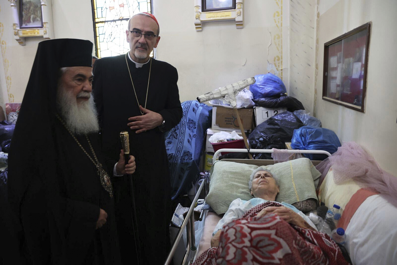 Den grekiskortodoxa patriarken av Jerusalem, Theophilos III, och den latinska patriarken Pierbattista Pizzaballa besöker en kvinna som skadades i Israels attack mot en katolsk kyrka i Gaza stad i juli. Foto: Latinska patriarkatet av Jerusalem via AP/TT