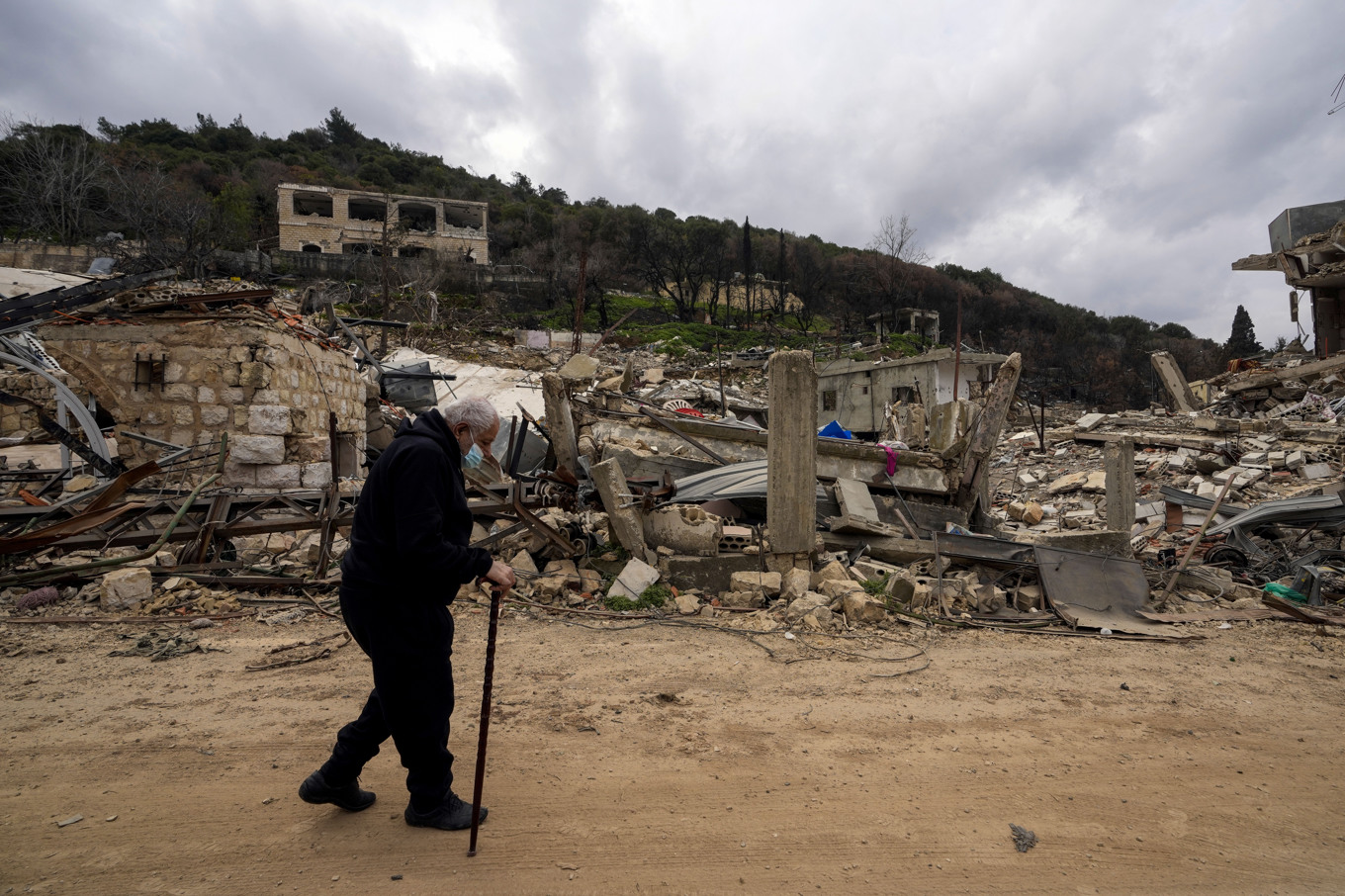 En man promenerar förbi ett område i södra Libanon som förstörts i samband med Israels markinvasion och luftangrepp. Bilden är tagen den 19 februari i år. Foto: Hassan Ammar/AP/TT