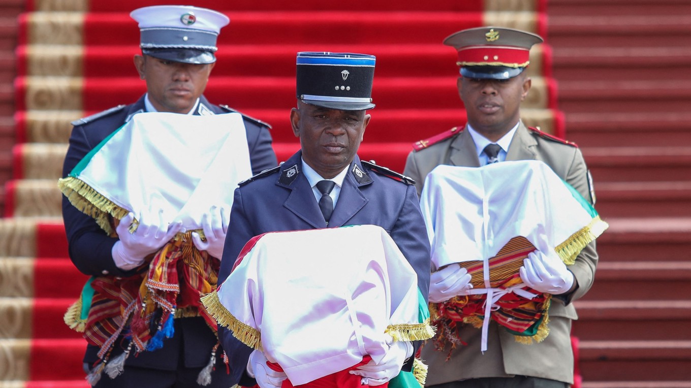 Den statliga ceremonin för återlämnandet av kranierna ägde rum vid ett mausoleum i Antananarivo i Madagaskar under tisdagen. Här bär tre tjänstemän kranierna. Foto: Mamyrael/AFP/TT