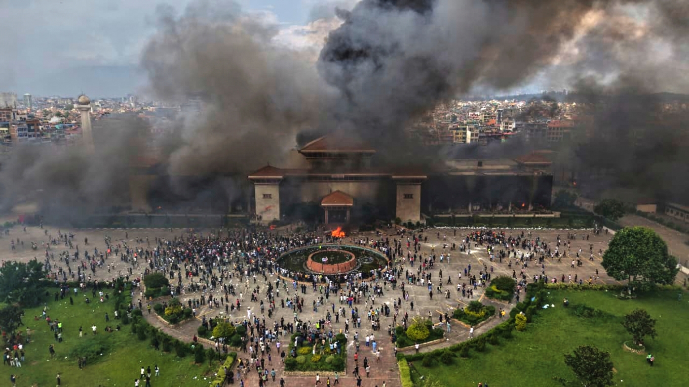 Demonstranter framför det brandstuckna parlamentet i Katmandu i tisdags. Foto: Prakash Timalsina/AP/TT