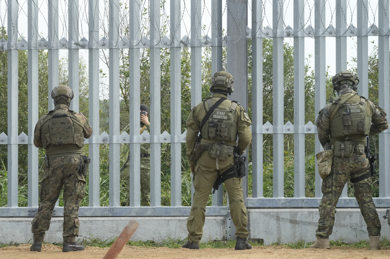Polska soldater tittar in i Belarus, där en belarusisk soldat tittar fram. Bild från augusti i år. Foto: Czarek Sokolowski/AP/TT
