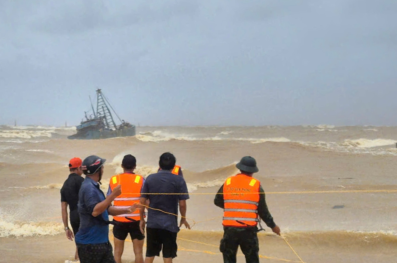En insats pågår för att rädda fiskare på en strandsatt fiskebåt i Quang Tri i Vietnam. Foto: Trinh Quoc Dung/AP/TT