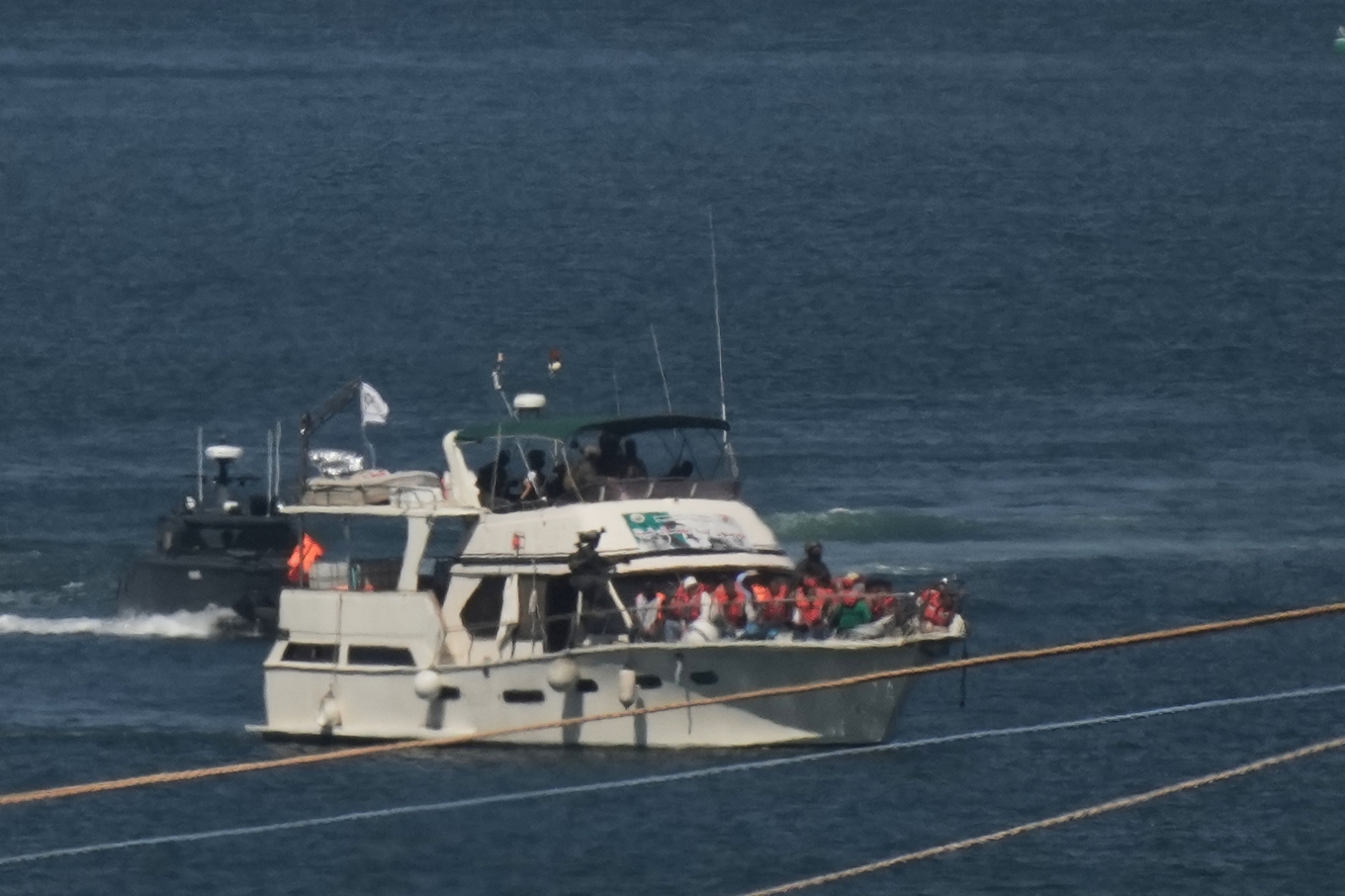 Aktivister i orangea flytvästar på en båt tillhörandes konvojen Global Sumud Flotilla som stoppats av israeliska marinen och eskorteras till israeliska hamnstaden Ashdod. Foto: Leo Correa/AP/TT