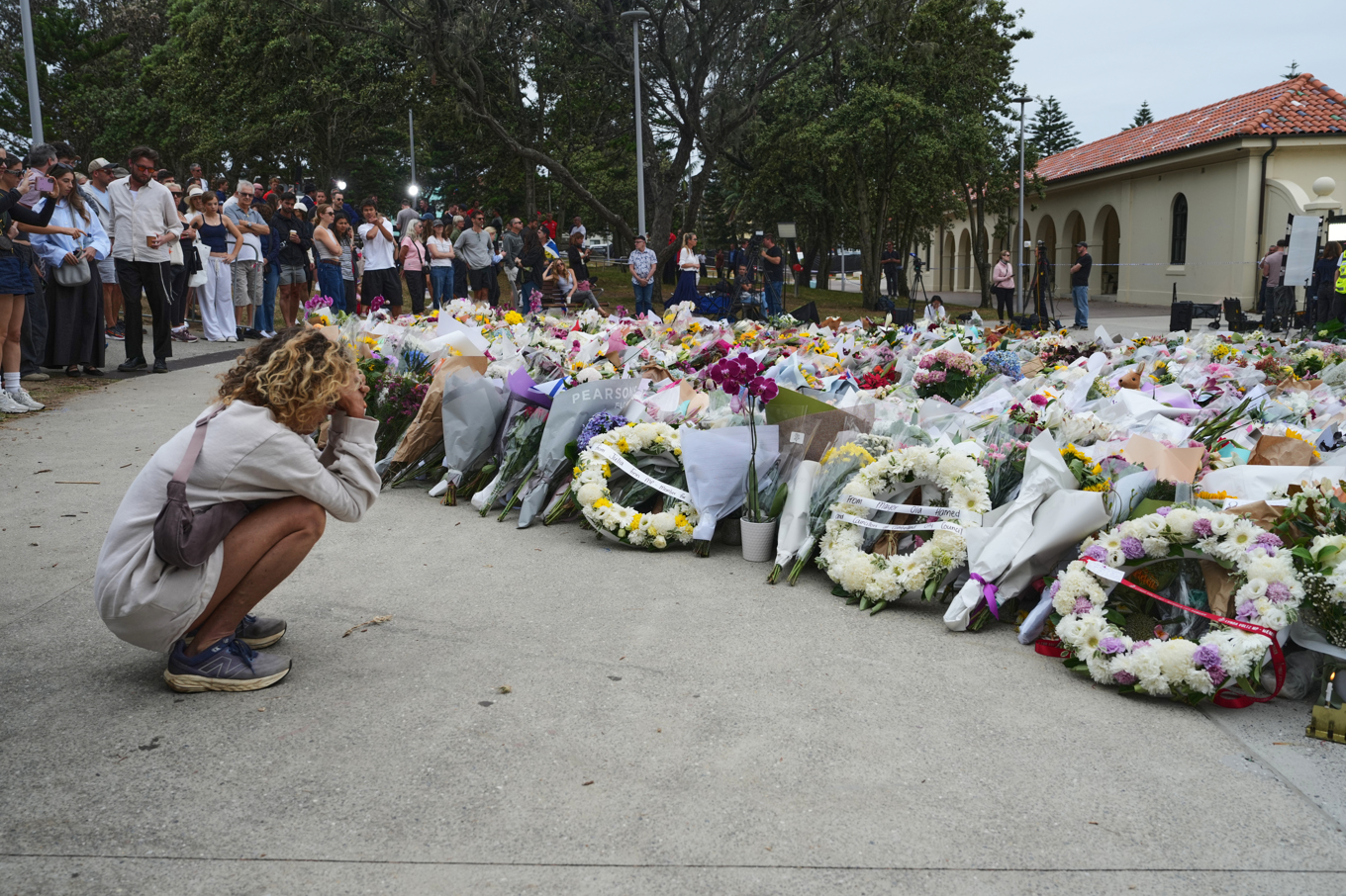 Sörjande samlas framför blommor på Bondi Beach där 15 människor dödades under söndagen. Foto: Mark Baker/AP/TT