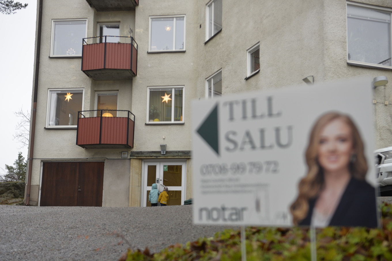Mäklarskylt framför bostadshus. Två barn framför porten. Arkivbild. Foto: Tove Eriksson/TT