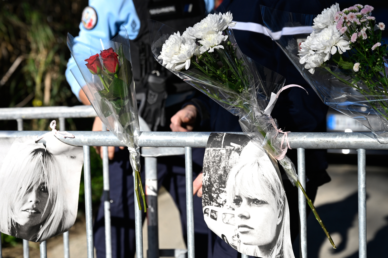 Blommor och bilder på den unga Brigitte Bardot prydde kravallstaketen när filmstjärnan begravdes i Saint-Tropez. Foto: Philippe Magoni/AP