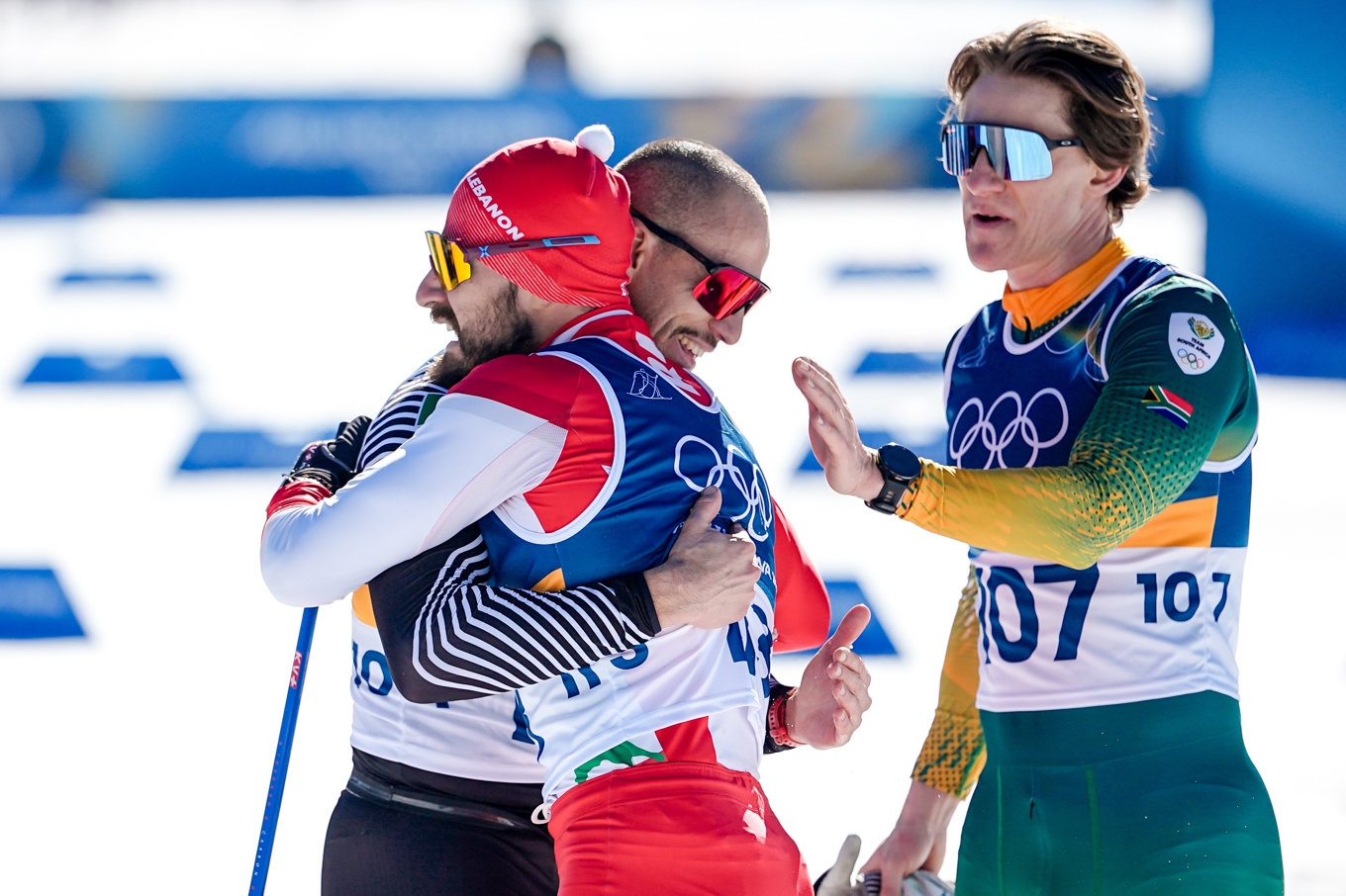 Samer Tuawk från Libanon, i mitten, gratuleras av mexikanen Allan Corona och Matthew Smith från Sydafrika efter att ha passerat mållinjen på 10 kilometer fristil under OS i Val di Fiemme. Foto: Matthias Schrader /AP/TT