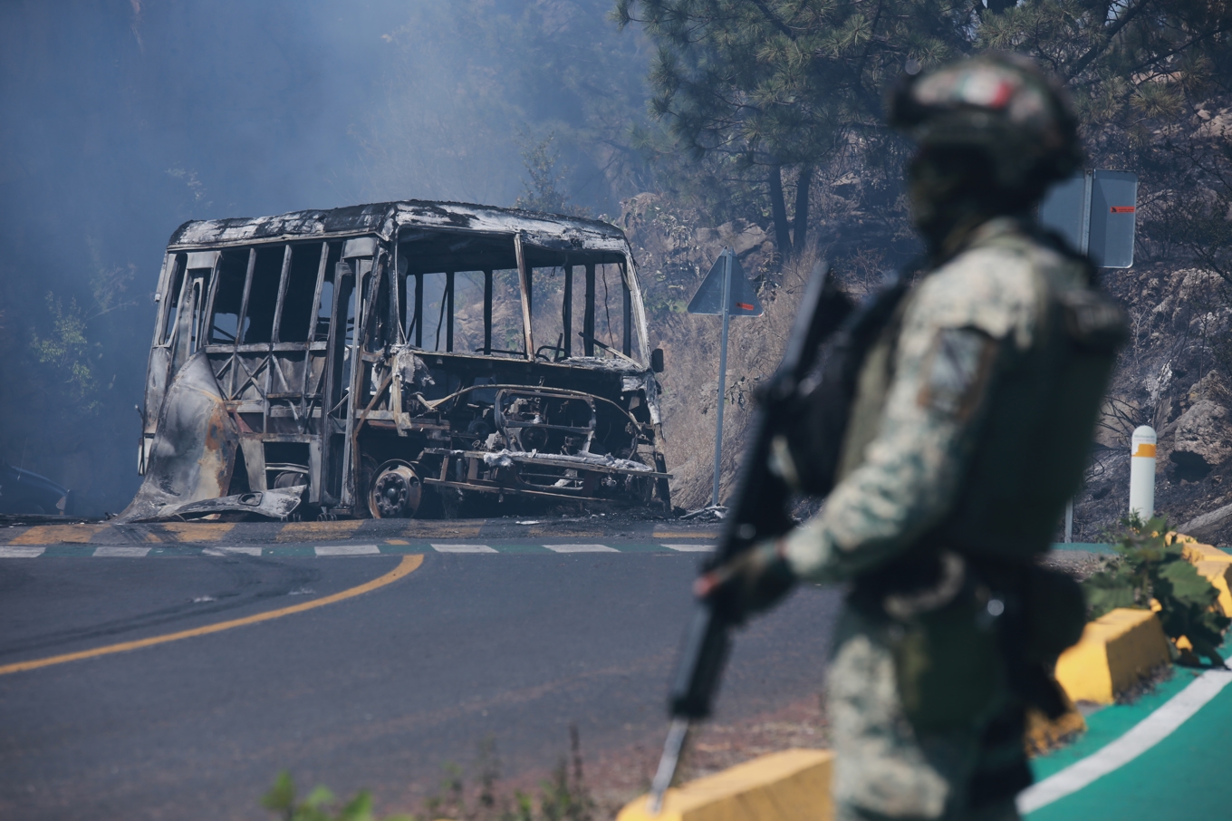En mexikansk soldat står som vakt vid ett nedbränt fordon efter att det satts i brand i Cointzio, i delstaten Michoacán. Foto: Armando Solis/AP/TT