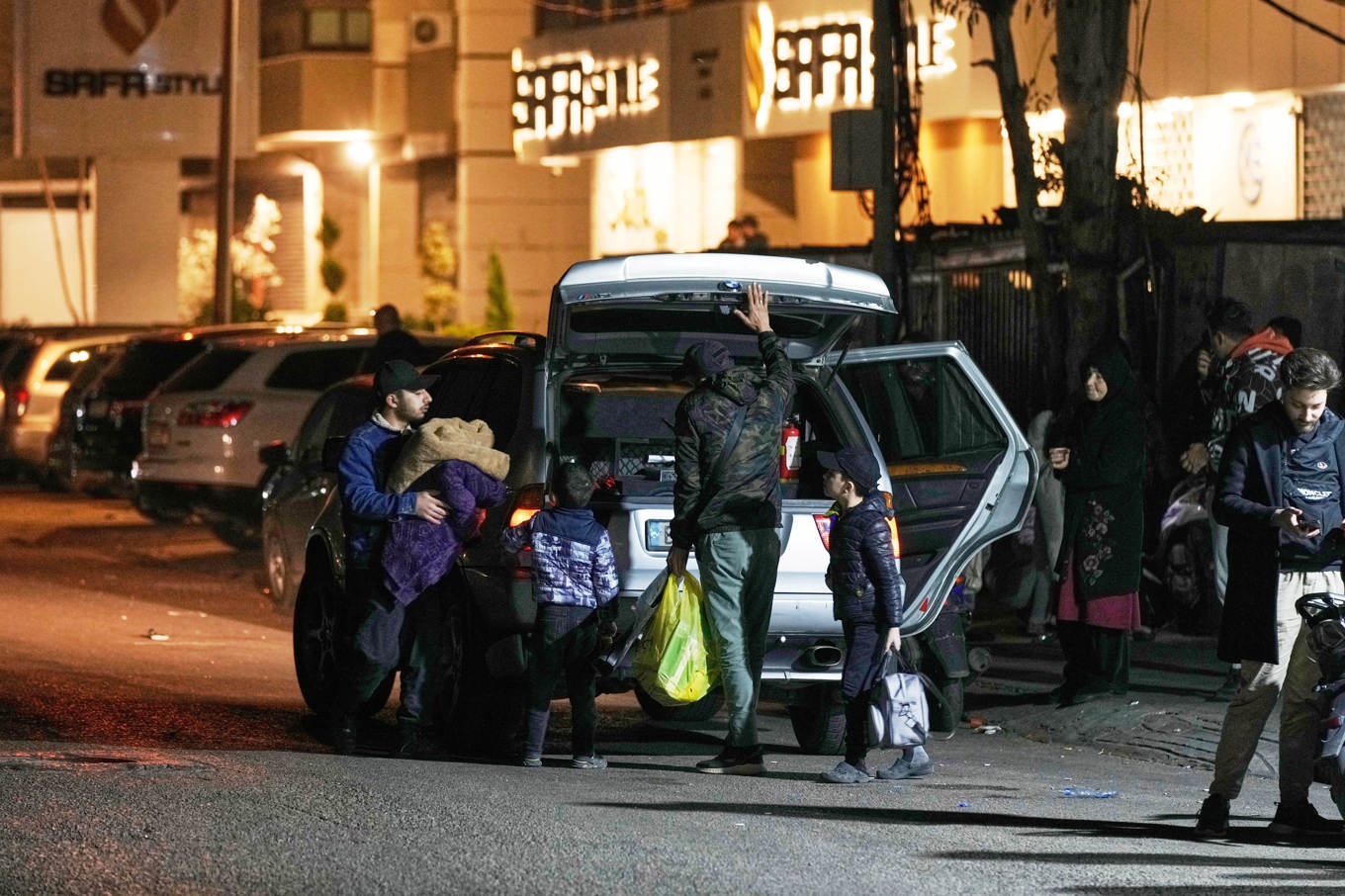 En familj lämnar sitt hem i samband med israeliska luftattacker mot Beiruts södra förorter. Foto: Bilal Hussein/AP/TT