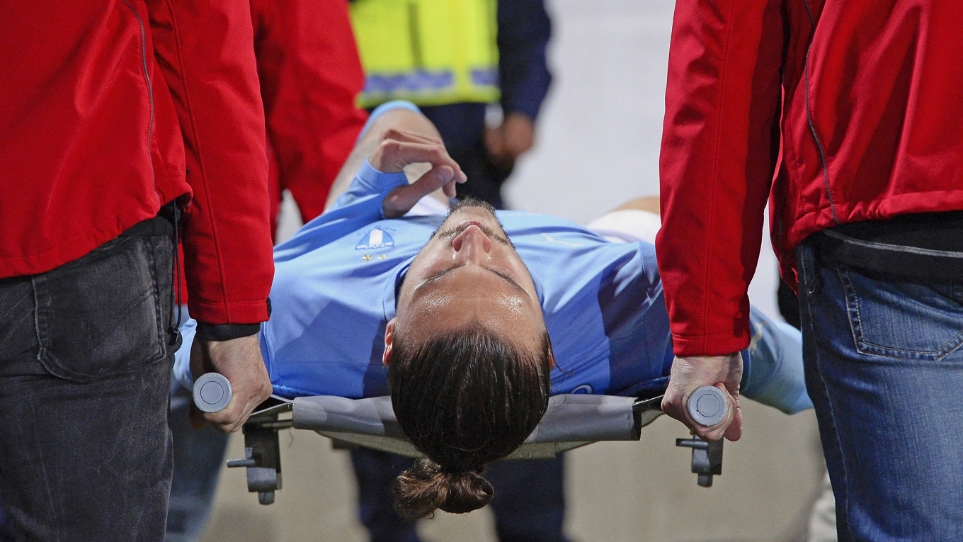 Erik Johansson, försvarare i Malmö FF, bärs ut på bår. Laget mötte Atlético Madrid den 4 november 2014. Skadan var som tur var ingen fraktur utan en bristning. Foto: Jonathan Näckstrand/AFP via Getty Images