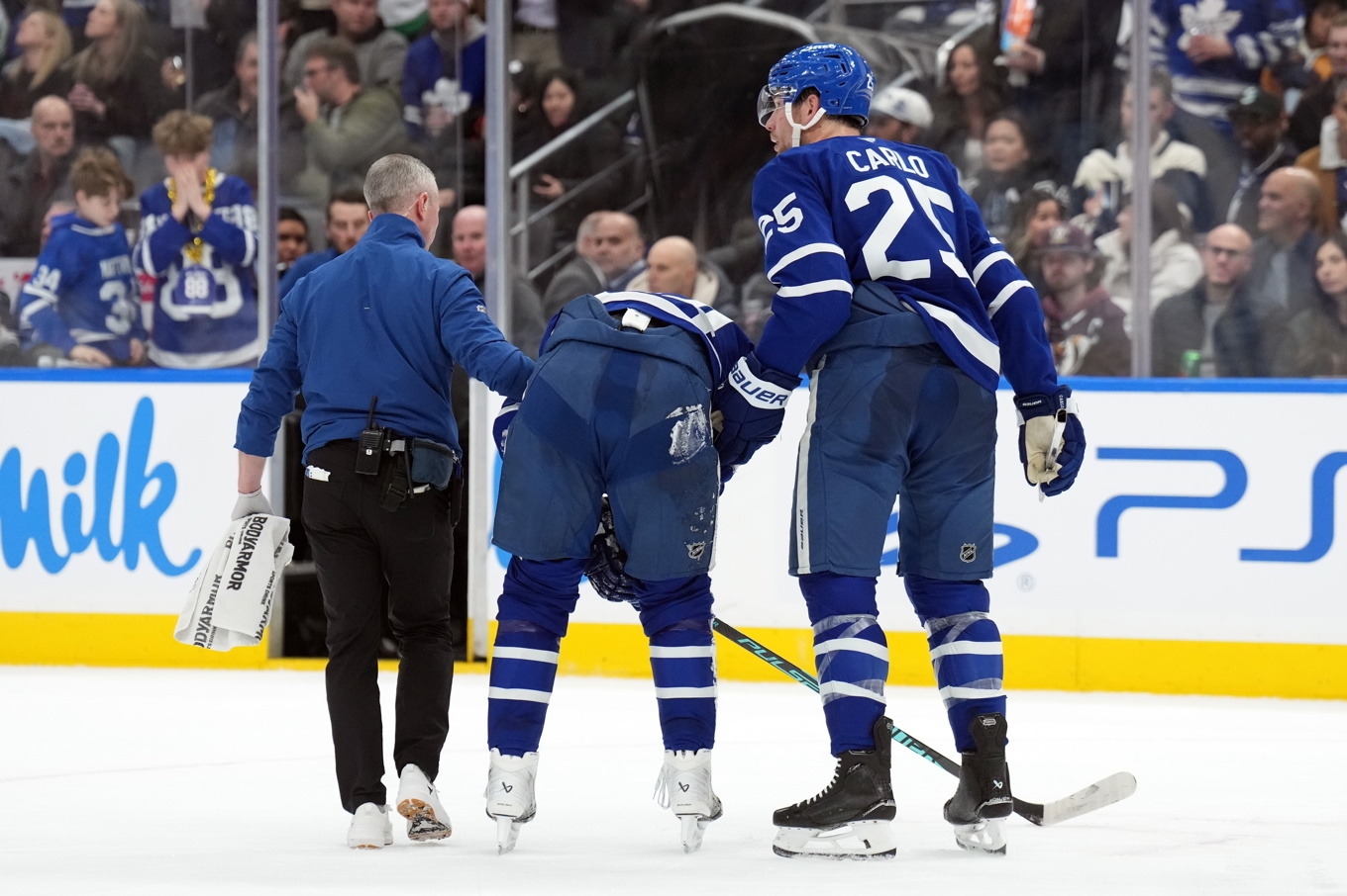 Torontos lagkapten Auston Matthews får hjälp att lämna isen efter att ha åkt på en knätackling. Foto: Nathan Denette/AP/TT