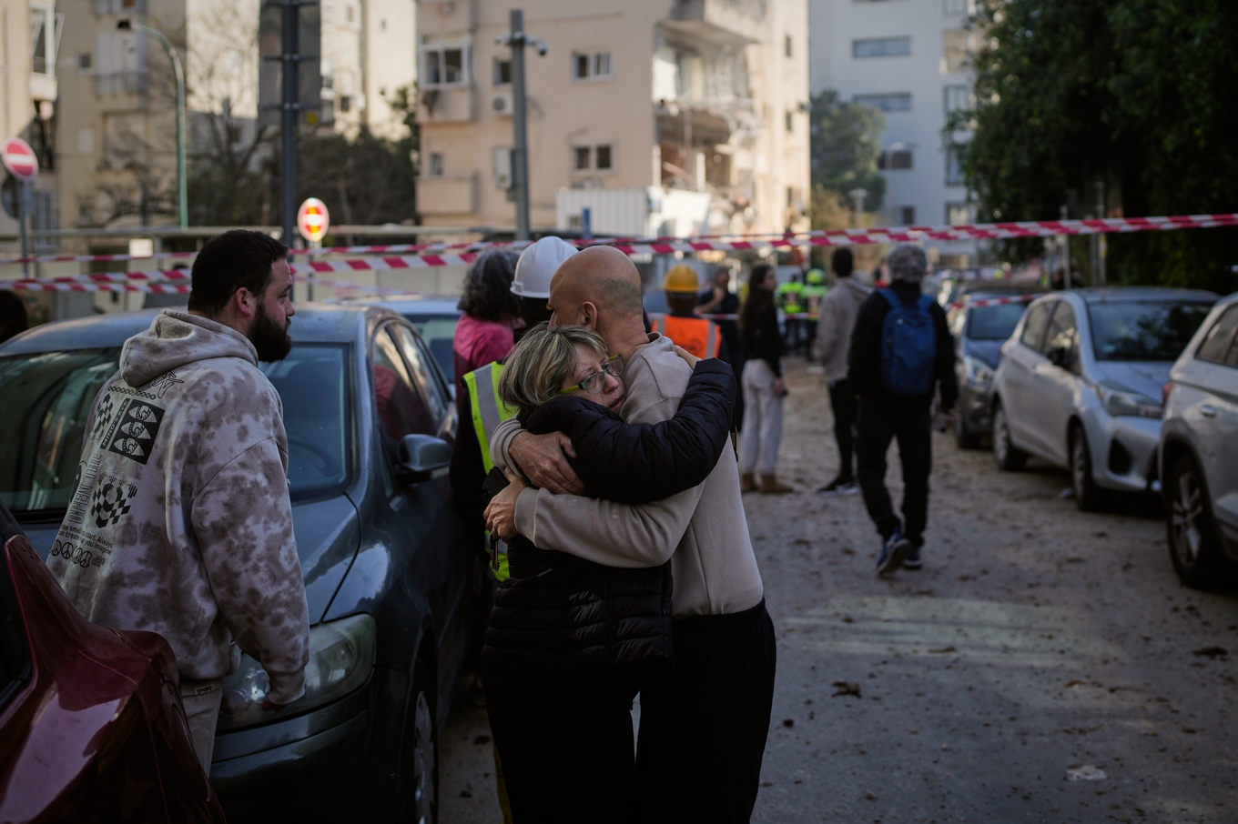 Två personer omfamnar varandra nära platsen för det iranska robotnedslaget i Tel Aviv på tisdagen. Foto: Ohad Zwigenberg/AP/TT