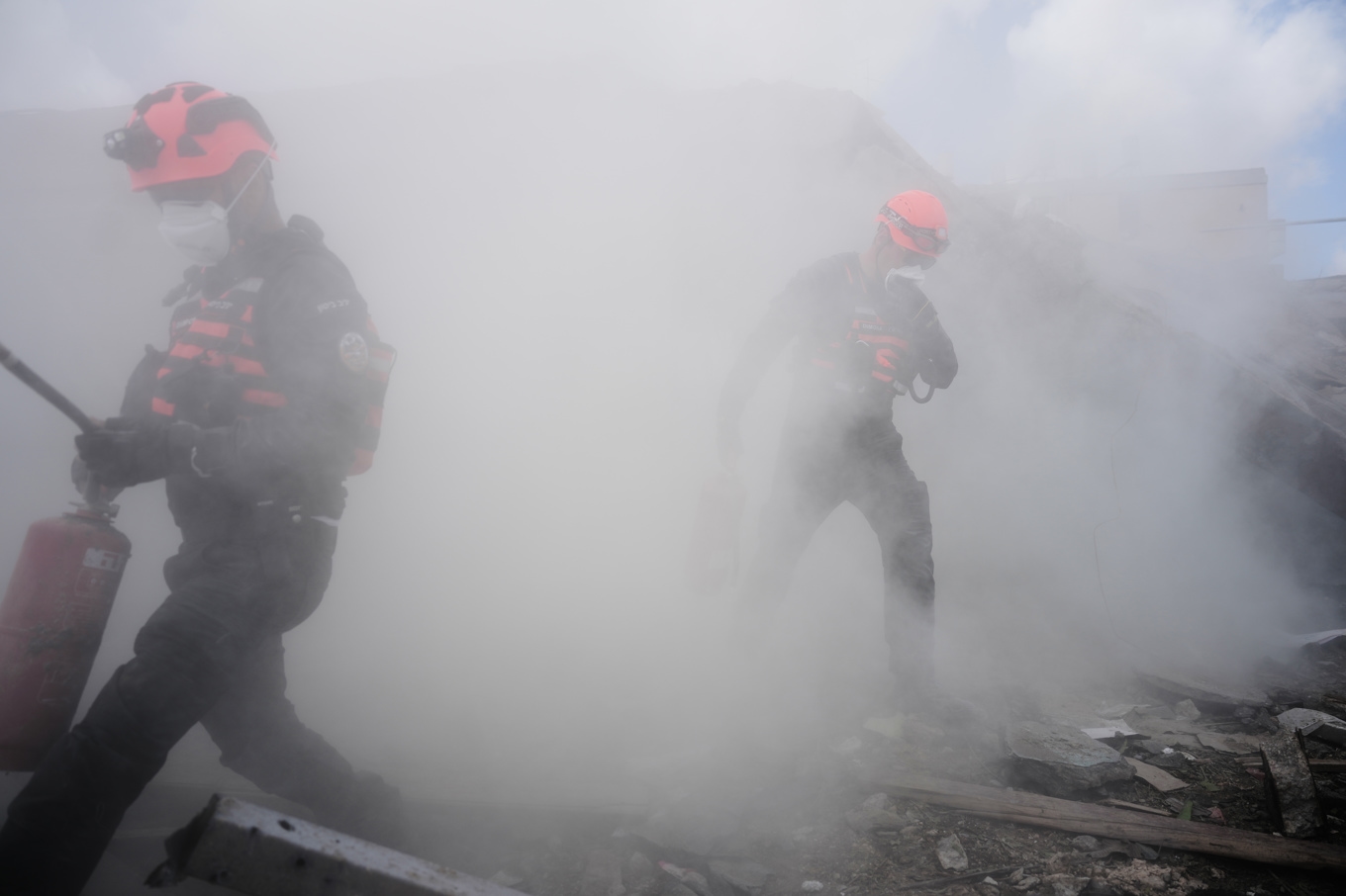 Brandmän släcker bränder i sönderbombade bostadshus i Dimona, efter lördagens iranska anfall mot området. Bilden togs på söndagen. Foto: Ariel Schalit/AP/TT