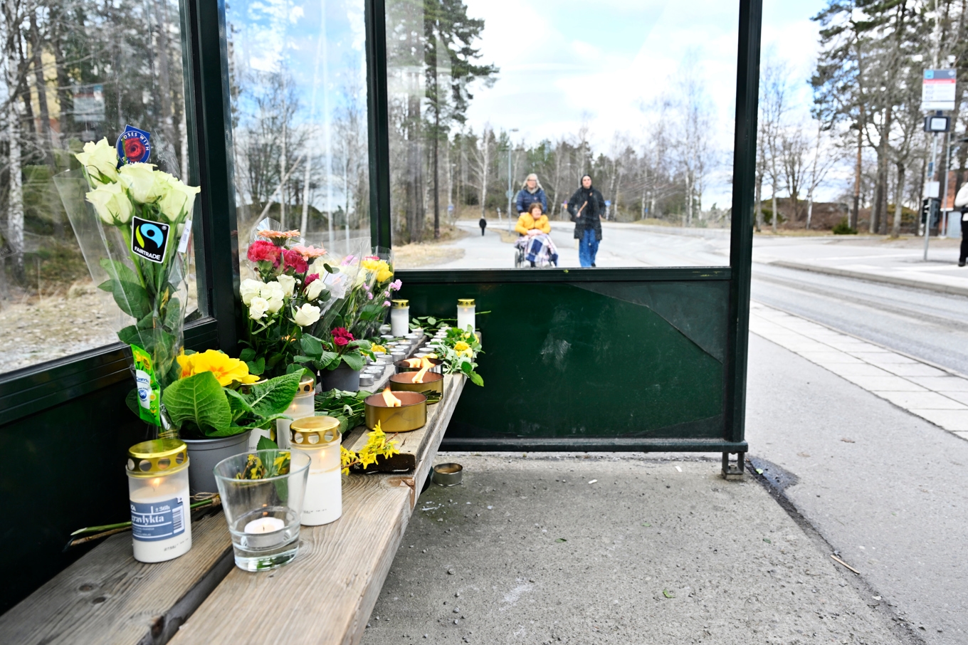 Blommor och ljus i en busskur efter att en man i 18-årsåldern blev skjuten på en buss vid platsen. Foto: Pontus Lundahl/TT