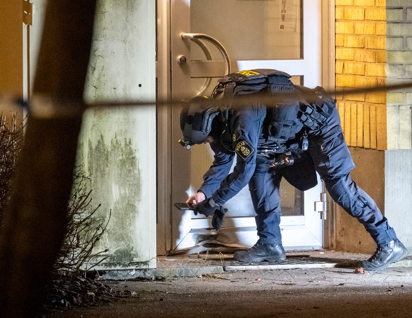 Polisens bombtekniker undersöker skadorna innanför avspärrningar vid ett flerfamiljshus i Bjuvs kommun. Foto: Johan Nilsson / TT