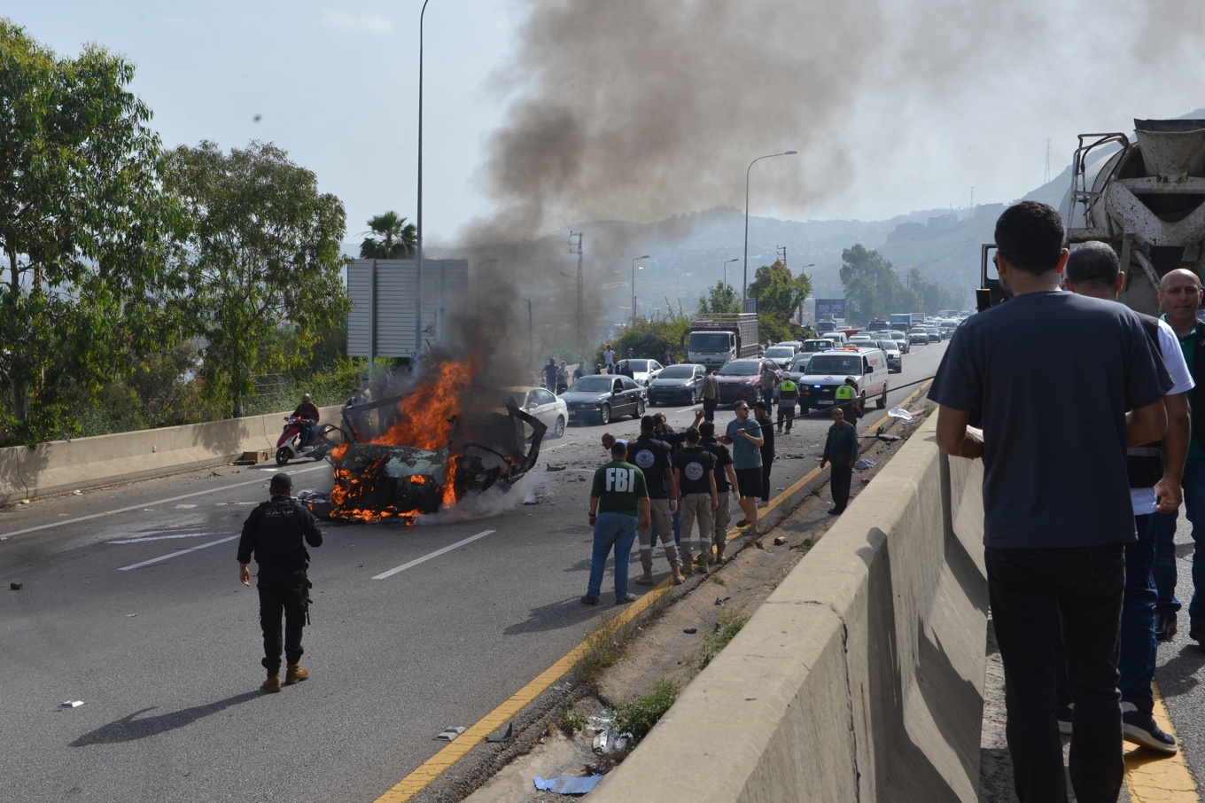 Säkerhets- och räddningspersonal runt en brinnande bil nära den libanesiska kuststaden Jiyeh. Bilen är en av flera som uppges ha träffats i en israelisk attack på onsdagen. Foto: Mustafa Jamalddine/AP/TT