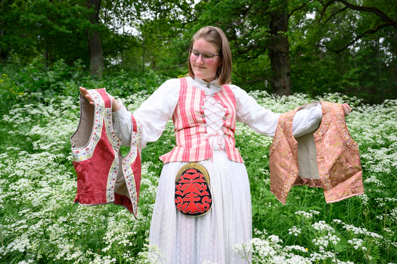 Folkdräkten är Matilda Nivert Öströms förstahandsval när det kommer till finkläder. På bilden bär hon Medelpadsdräkten och håller upp två västar som kan bäras till Blekingedräkten. Foto: Jessica Gow/TT