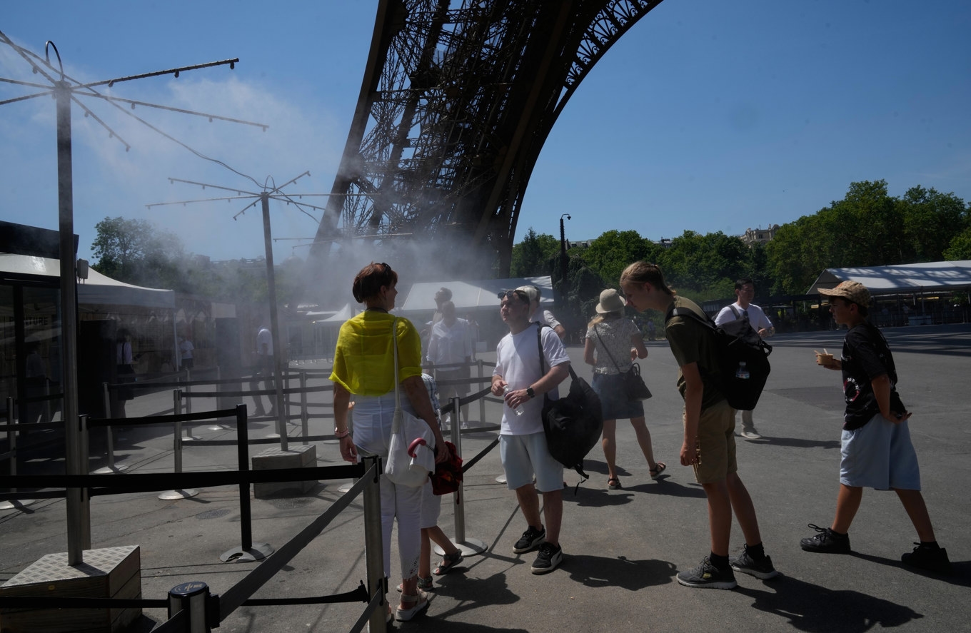 Människor svalkar sig vid Eiffeltornet i Paris på söndagen. Foto: Michel Euler/AP/TT