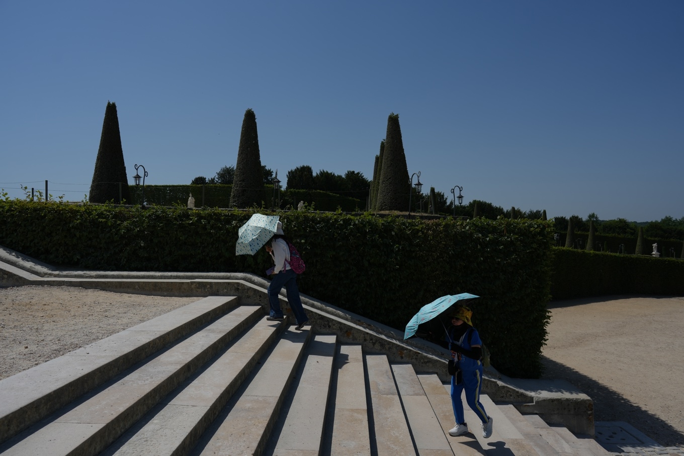 Besökare till slottet i Versailles utanför Paris skyddar sig mot solen med hjälp av paraplyer när temperaturen stiger över 40 grader. Foto: Thibault Camus/AP/TT