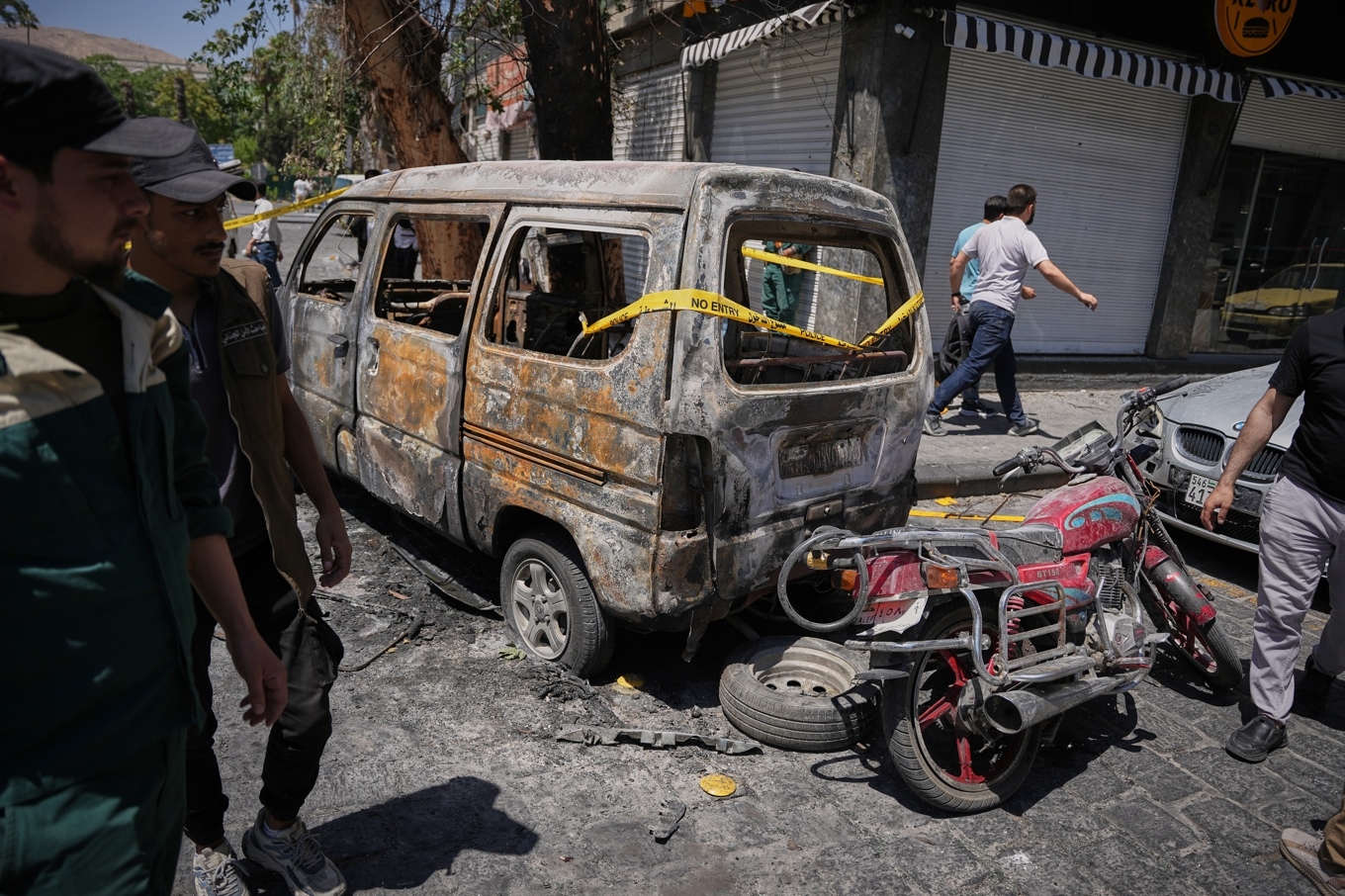 Syriskt säkerhetspersonal undersöker resterna av en bil som demolerades i explosionen nära hotellet Four Seasons den 7 juli. Foto: Omar Albam /AP/TT