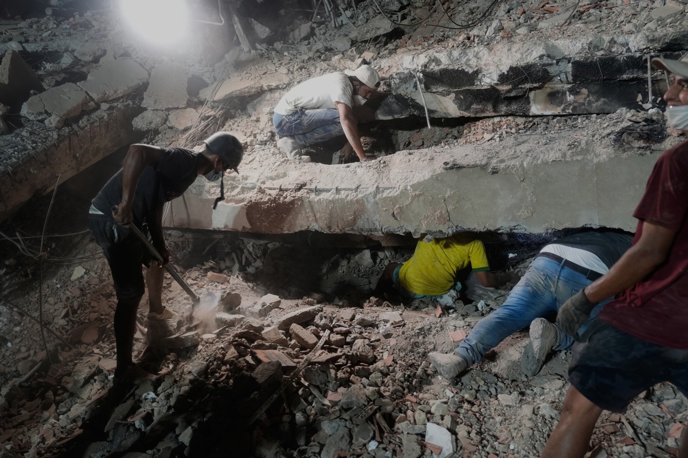 En familj letar efter anhöriga under rasmassorna i La Guaira, den 9 juli. Foto: Ariana Cubillos /AP/TT
