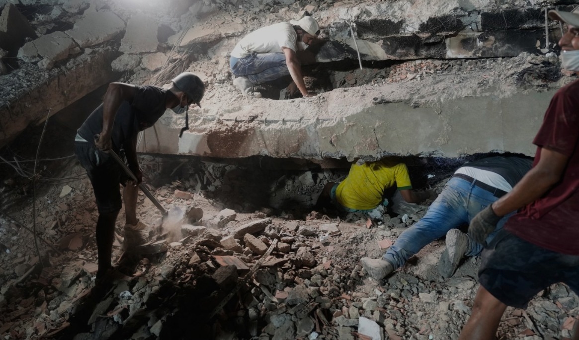 En familj söker efter anhöriga i rasmassorna av en kollapsad byggnad i staden La Guaira, Venezuela. Bild från torsdagen. Foto: Ariana Cubillos/AP/TT
