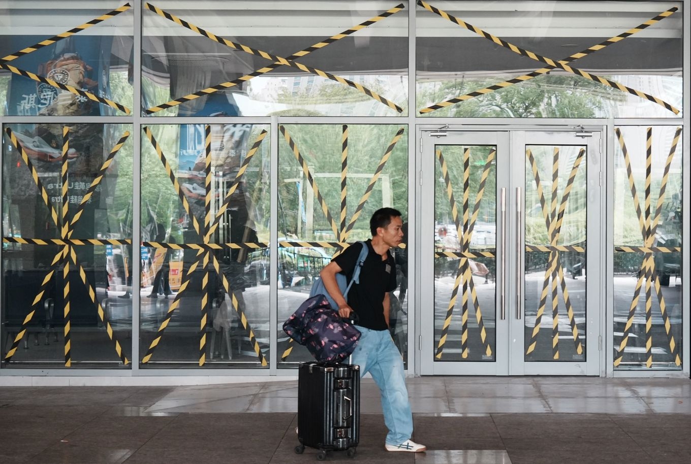 En passagerare går förbi en busstation där alla glasfönster och dörrar har förstärkts med skyddstejp inför tyfonen Dolphin i Hangzhou i den östra kinesiska provinsen Zhejiang, på söndagen 9 augusti. Foto: Chinatopix/AP/TT