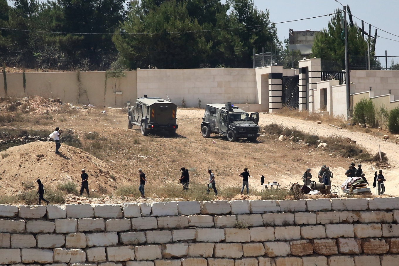 Israeliska soldater står vakt bredvid bosättare framför palestinska bostäder som de har blockerat i byn Qusra, söder om Nablus, på den ockuperade Västbanken. Foto: Nidal Ishtaya/AP/TT