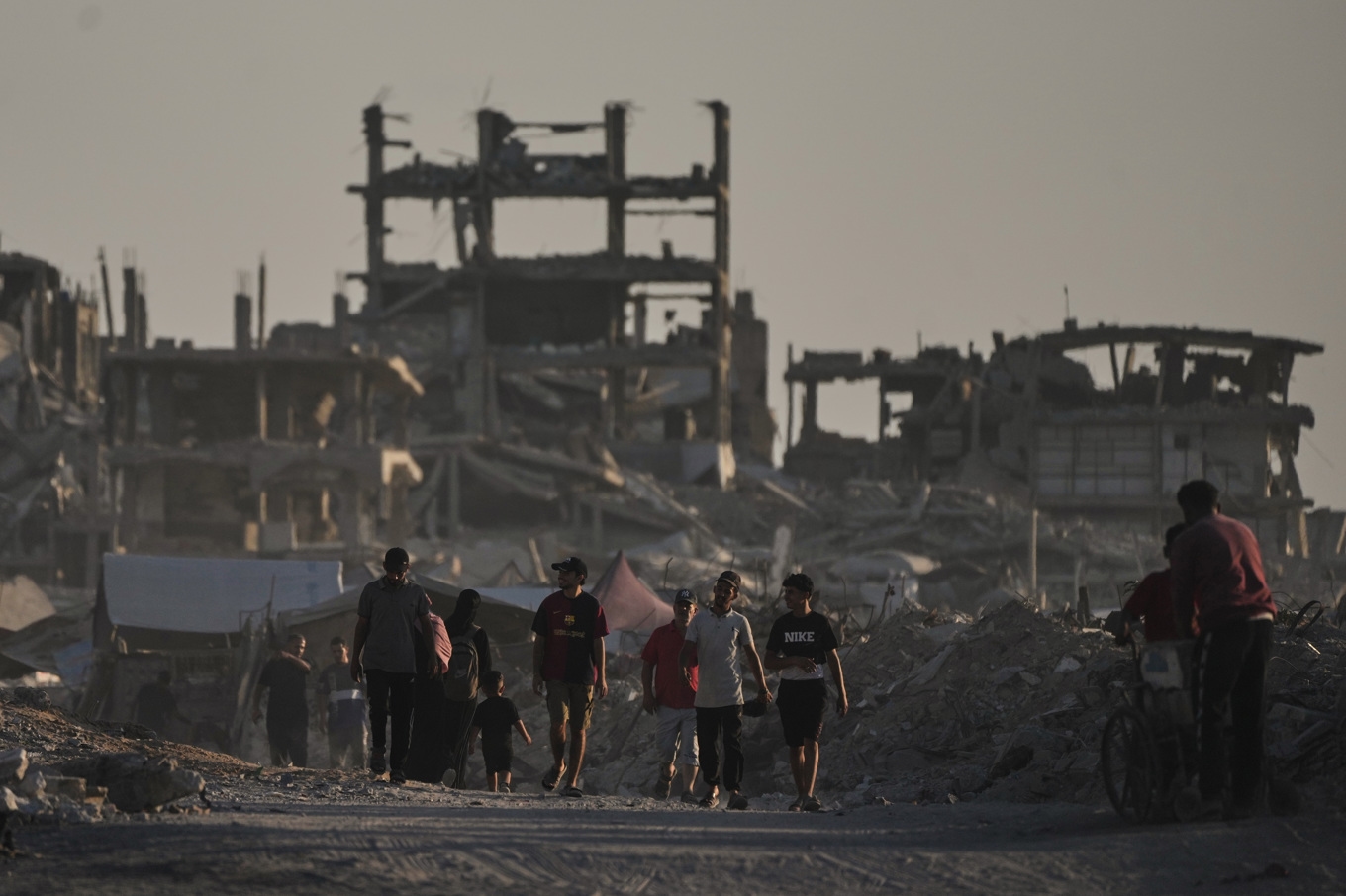 Palestinier framför en bombad byggnad i Gaza stad, där hjälpbehovet är enormt, under måndagen. Foto: Jehad Alshrafi/AP/TT
