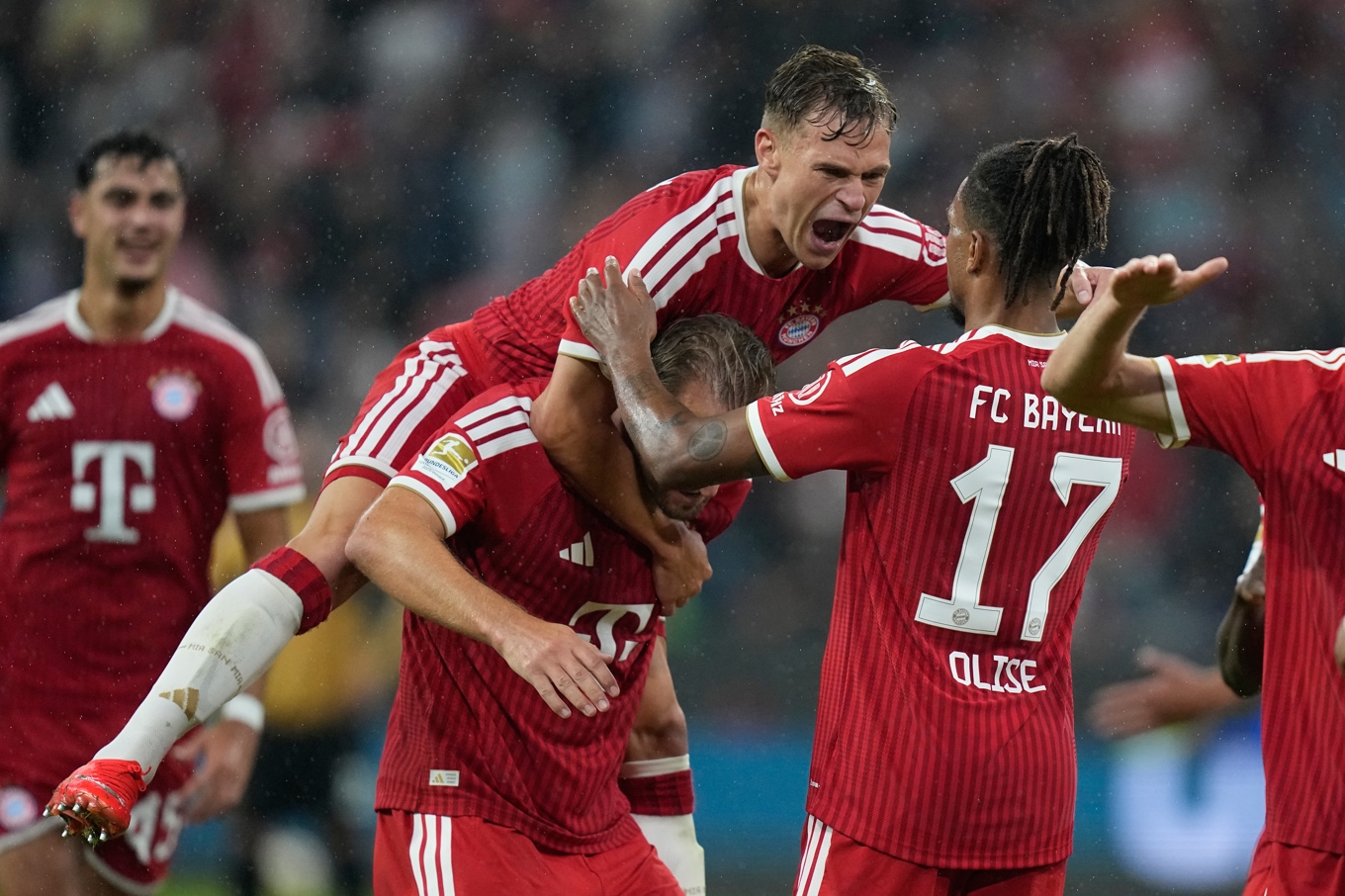 Bayern München-spelarna Michael Olise, Joshua Kimmich, och Harry Kane firar under Bundesligapremiären mot Stuttgart. Foto: Matthias Schrader/AP/TT