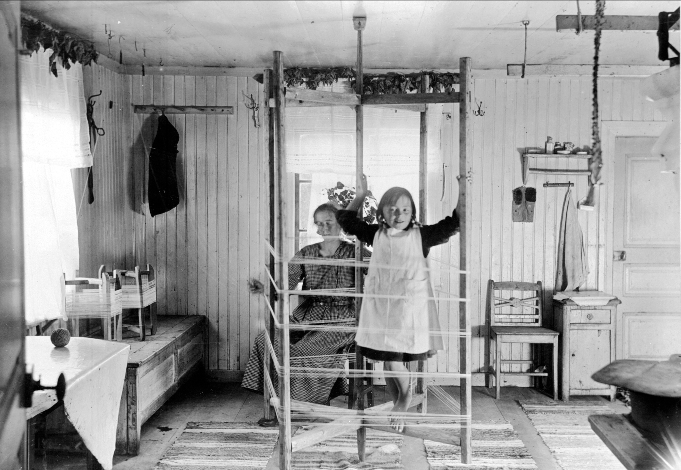En flicka klättrar på en varpställning i hemmet. Foto: Nils Keyland
