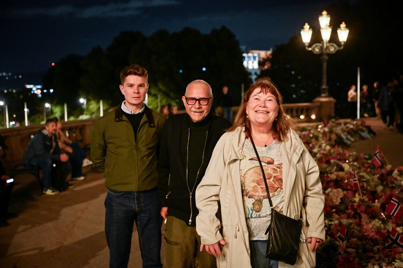 Osloborna Hans Bjørner, Sigmund Norderhos och Hilde Østrem vid blomsterhavet utanför kungliga slottet i Oslo kvällen inför begravningen. Foto: Pontus Lundahl/TT
