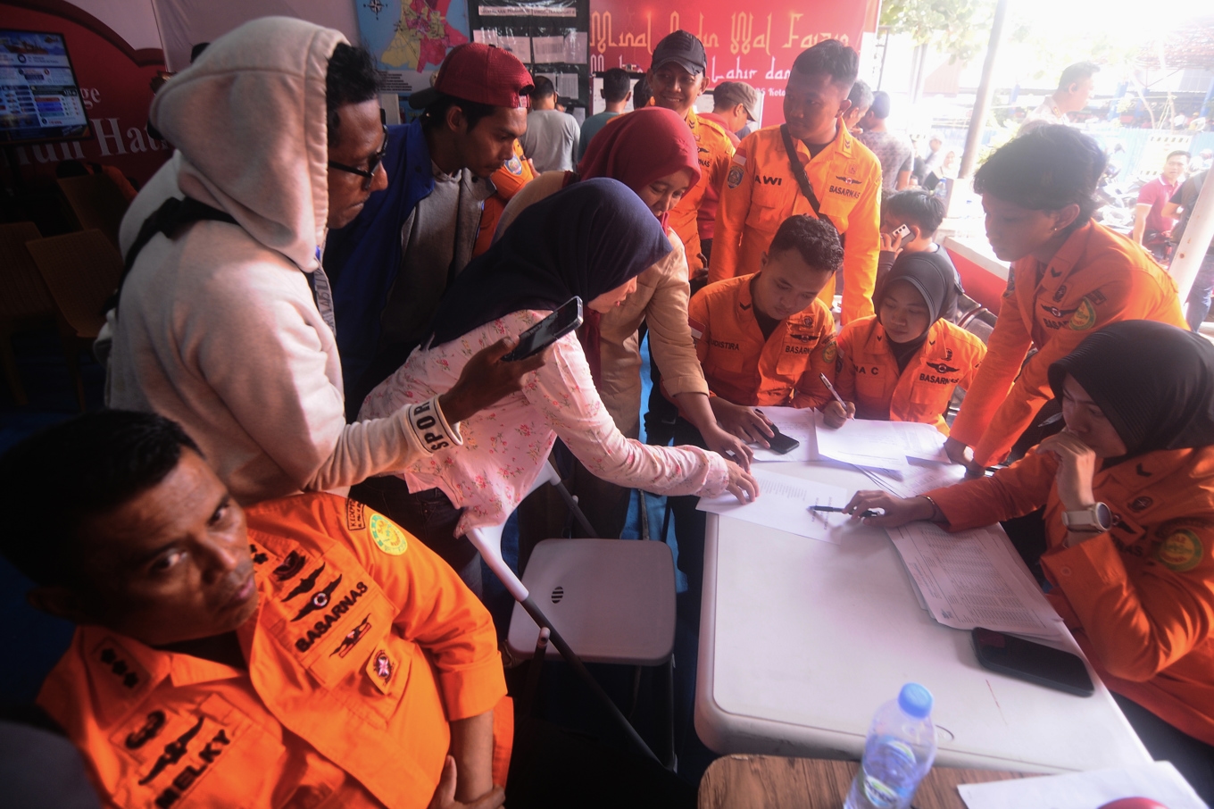 Anhöriga söker på passagerarlistor efter namn på familjemedlemmar, efter färjeolyckan i Indonesien. Foto: Iman Satria/AP/TT