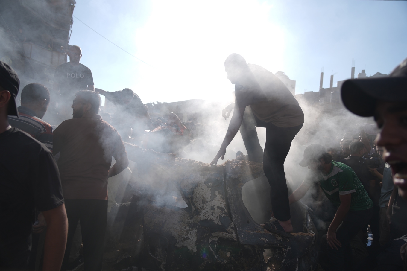 Människor söker igenom ett förstört fordon efter en av attacken nära Gaza stad på lördagen. Foto: Jehad Alshrafi/AP/TT