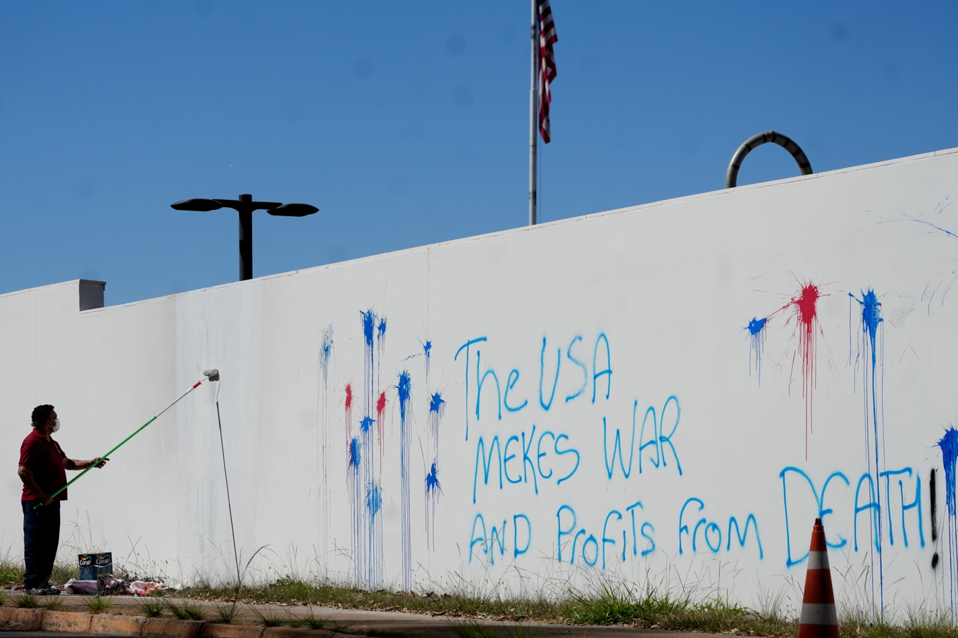 En man sanerar graffiti på muren till USA:s ambassad i huvudstaden Brasilia. Arkivbild. Foto: Eraldo Peres /AP/TT