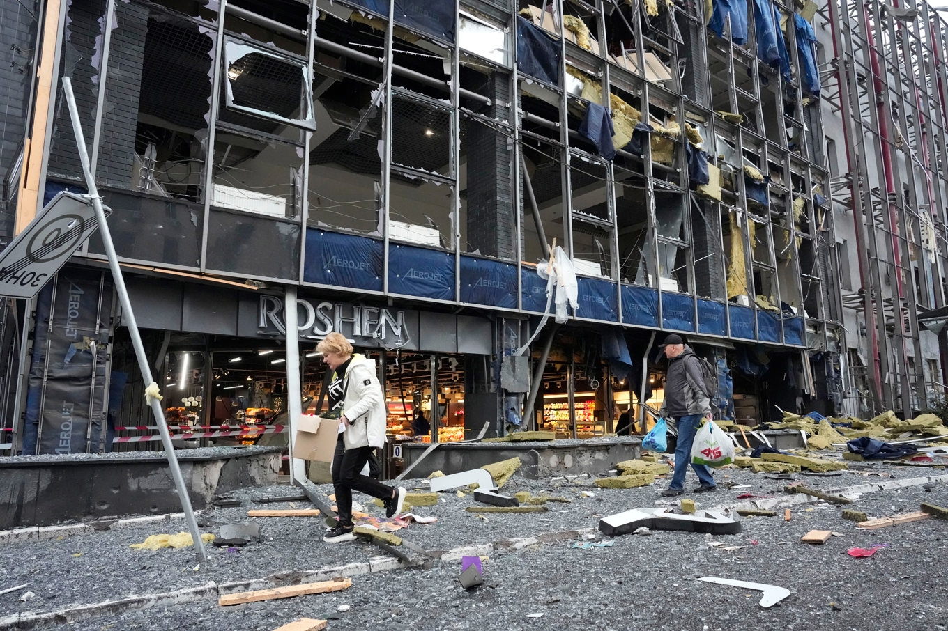 Kievbor går undan med sina tillhörigheter efter ett anfall mot deras kontorsbyggnad i Kiev på måndagen. Foto: Efrem Lukatsky/AP/TT