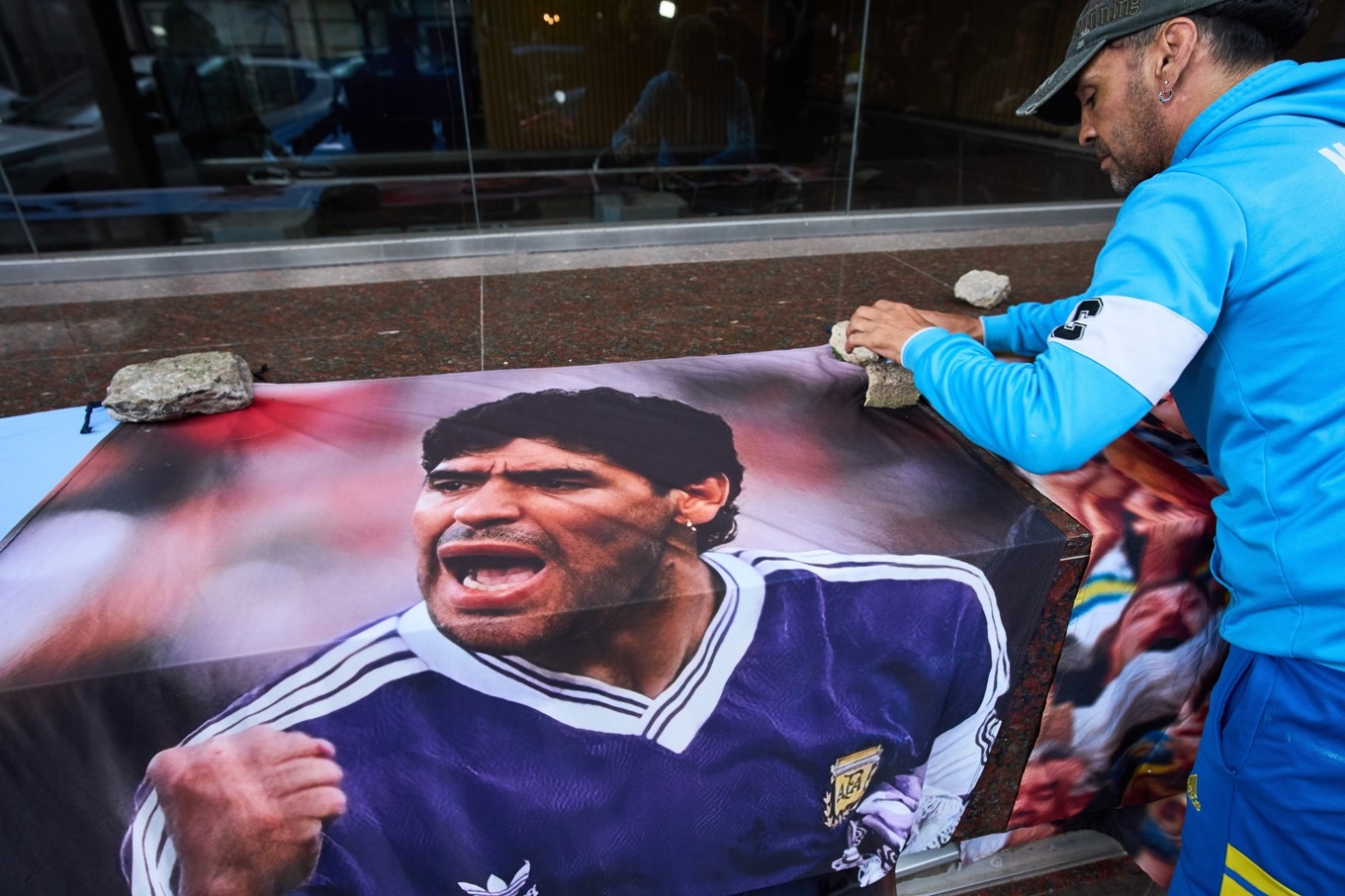 En flagga som pryds av Diego Maradona läggs ut av ett fan utanför domstolen i San Isidro utanför Buenos Aires. Foto: Rodrigo Abd/AP/TT