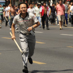 En hankines jagar en fotograf för att få honom sluta ta bilder då tusentals kineser marscherade runt på gatorna i Urumqi den 7 juli och krävde hämnd.