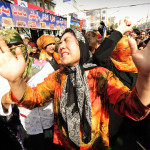 Obeväpnade muslimska etniska uigurkvinnor gråter och protesterar mot att deras män forsvunnit i Urumqi.