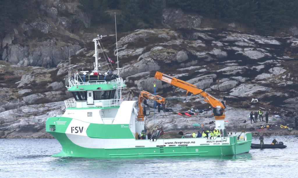 Vraket av den kraschade helikoptern bärgas av en kranbåt. (Foto: Vidar Ruud/NTB scanpix/TT)