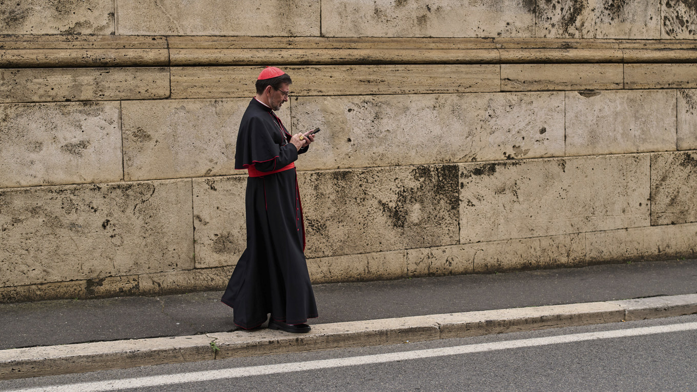 Kardinalen José Cobo Cano passar på att använda sin mobiltelefon innan nätet släcks i Vatikanen. Bild från slutet av april. Foto: Bernat Armangue/AP/TT