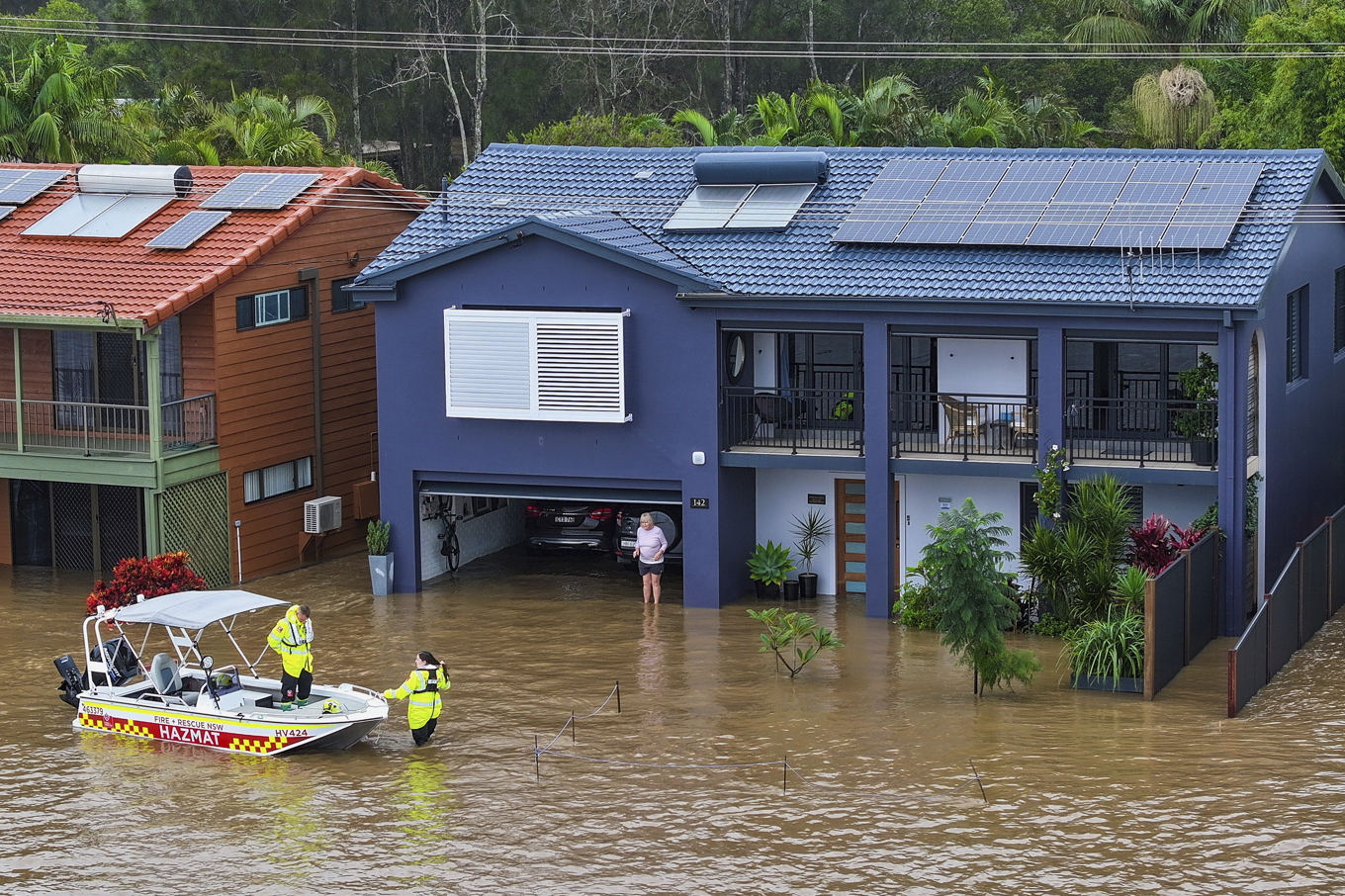 Räddningspersonal bistår en person som strandsatts i sin översvämmade bostad i Port Maquarie i delstaten New South Wales i Australien på torsdagen. Foto: Lindsay Moller/AAP via AP/TT