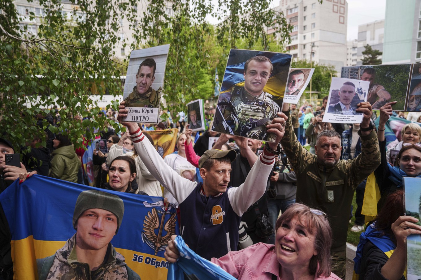 Anhöriga till saknade och fängslade ukrainska soldater håller upp bilder på sina saknade i samband med att soldater återvänder vid en tidigare fångutväxling i början av maj. Foto: Evgeniy Maloletka/AP/TT