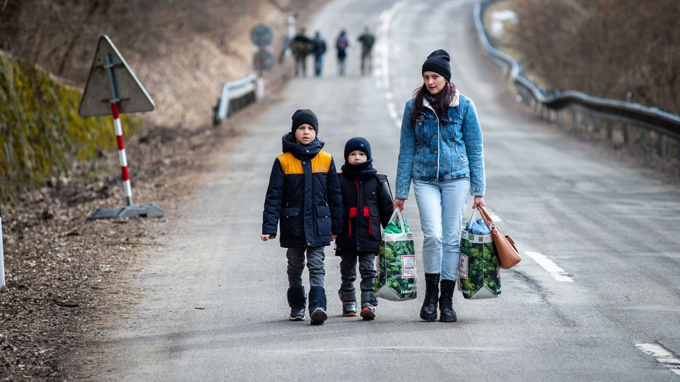 En ukrainsk kvinna med två barn går på en väg vid den slovakiska gränsen. Bilden är tagen den 25 februari 2022. Foto: Peter Lazar/AFP via Getty Images